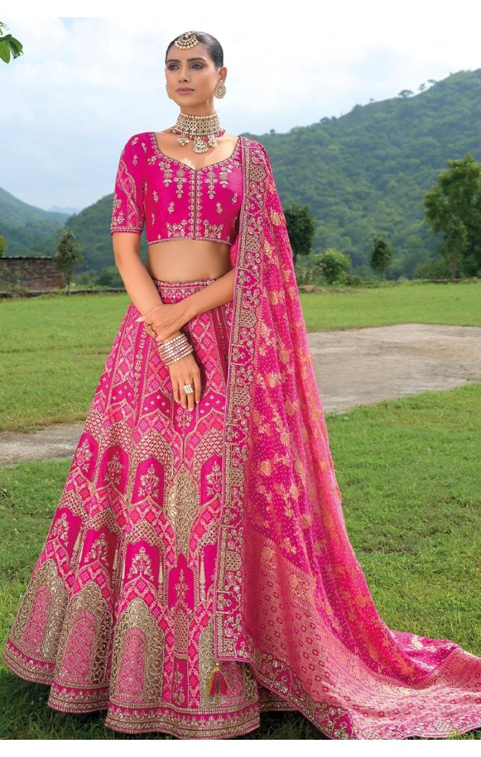 A royal pink Banarasi lehenga with gold zari work and intricate embroidery, perfect for Indian weddings and festive celebrations.