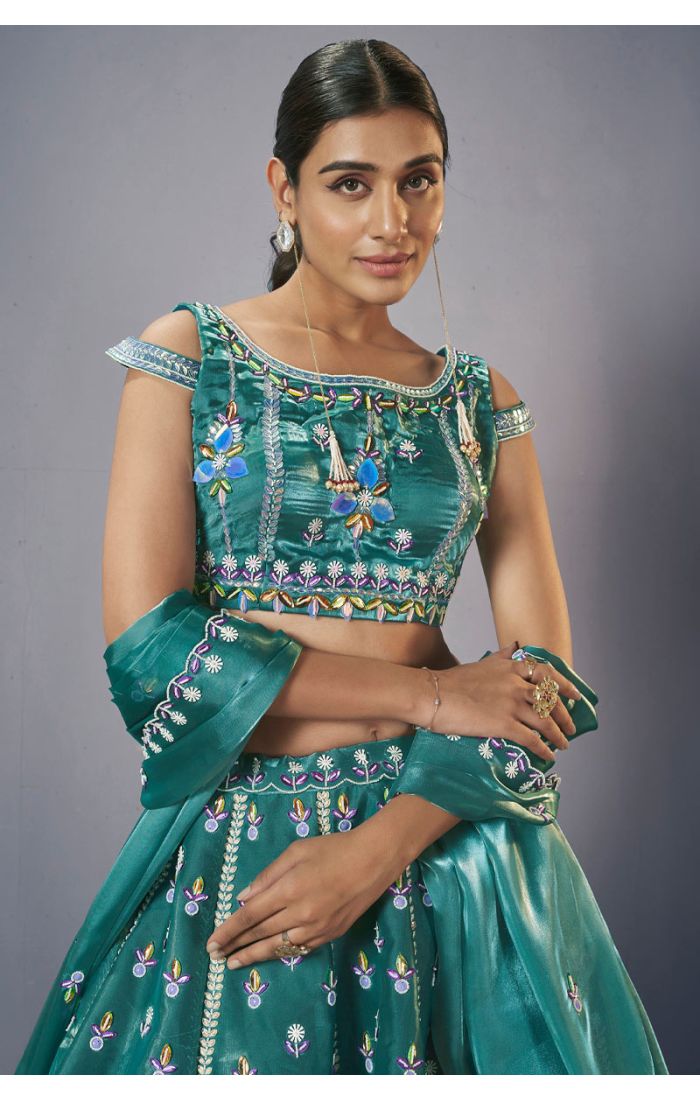 Close-up of teal green designer lehenga choli blouse with multicolour embroidery and mirror work detailing