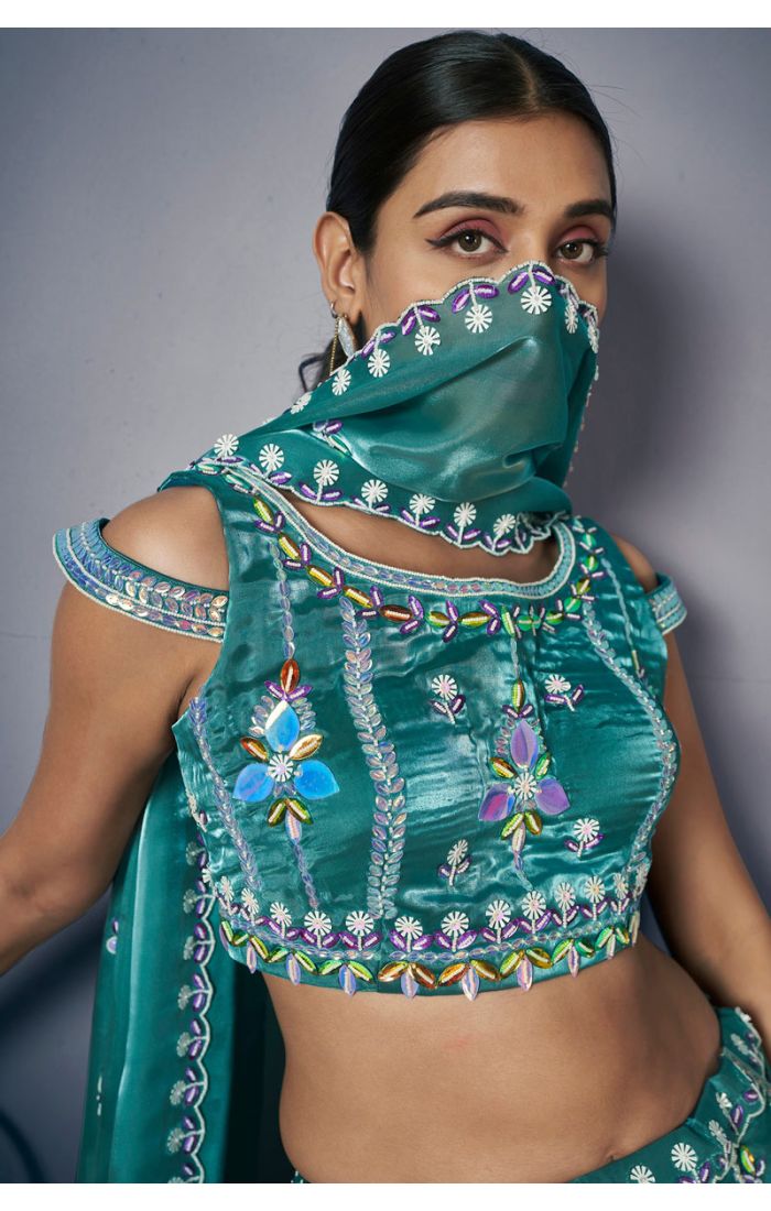 Close-up of teal green designer lehenga choli blouse with multicolour embroidery and mirror work detailing
